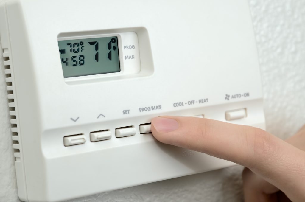 finger pressing button  on digital thermostat
